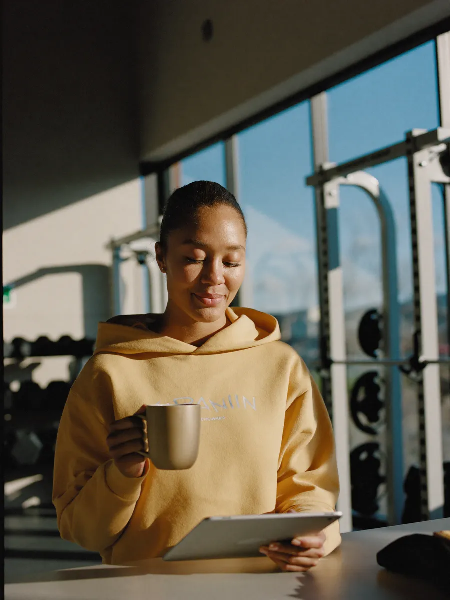 A gym owner with a coffee and tablet in the morning, reviewing the inquiries GymGreeter handled overnight.